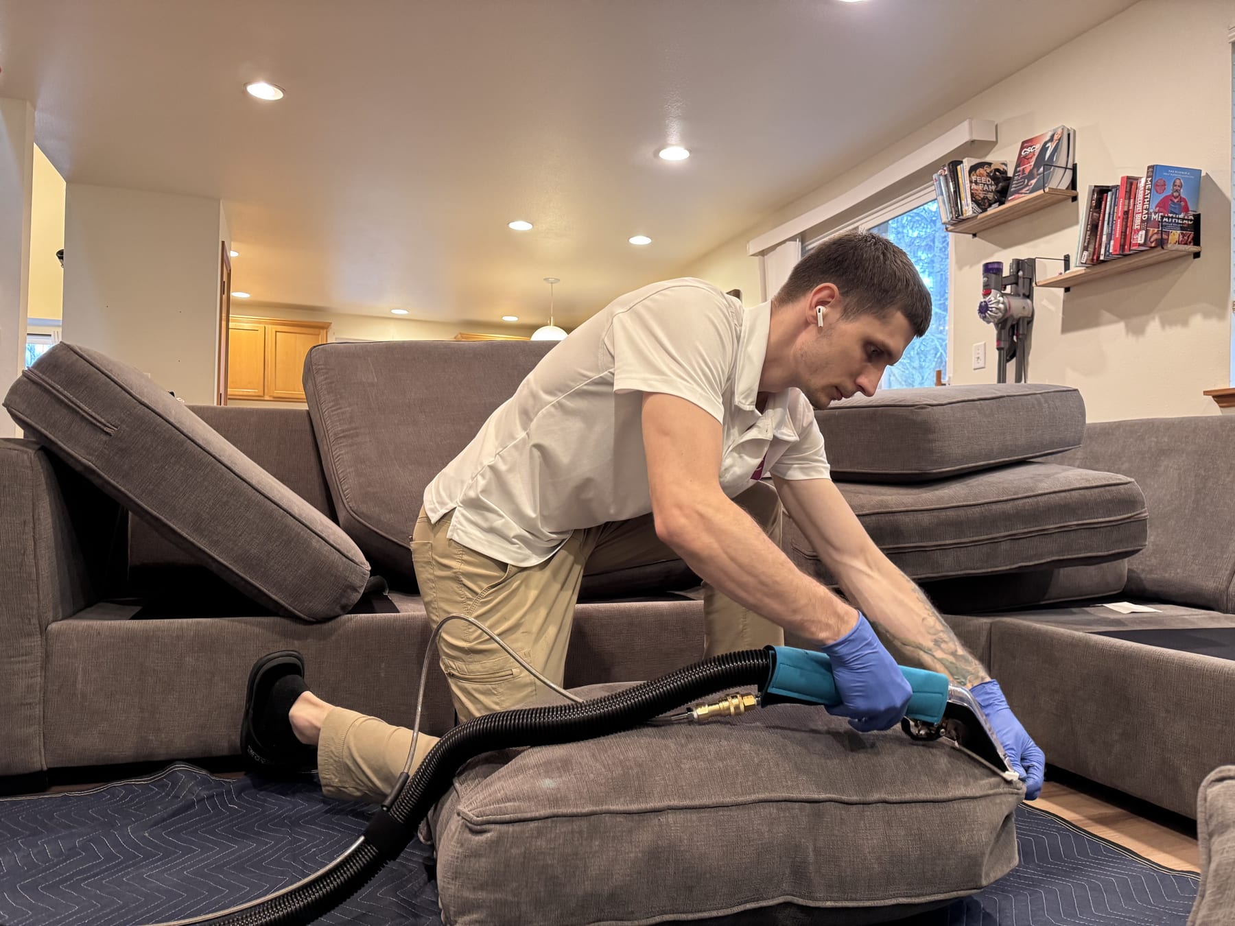 MagiClean technician using professional hot-water extraction on a fabric couch cushion in a Seattle home