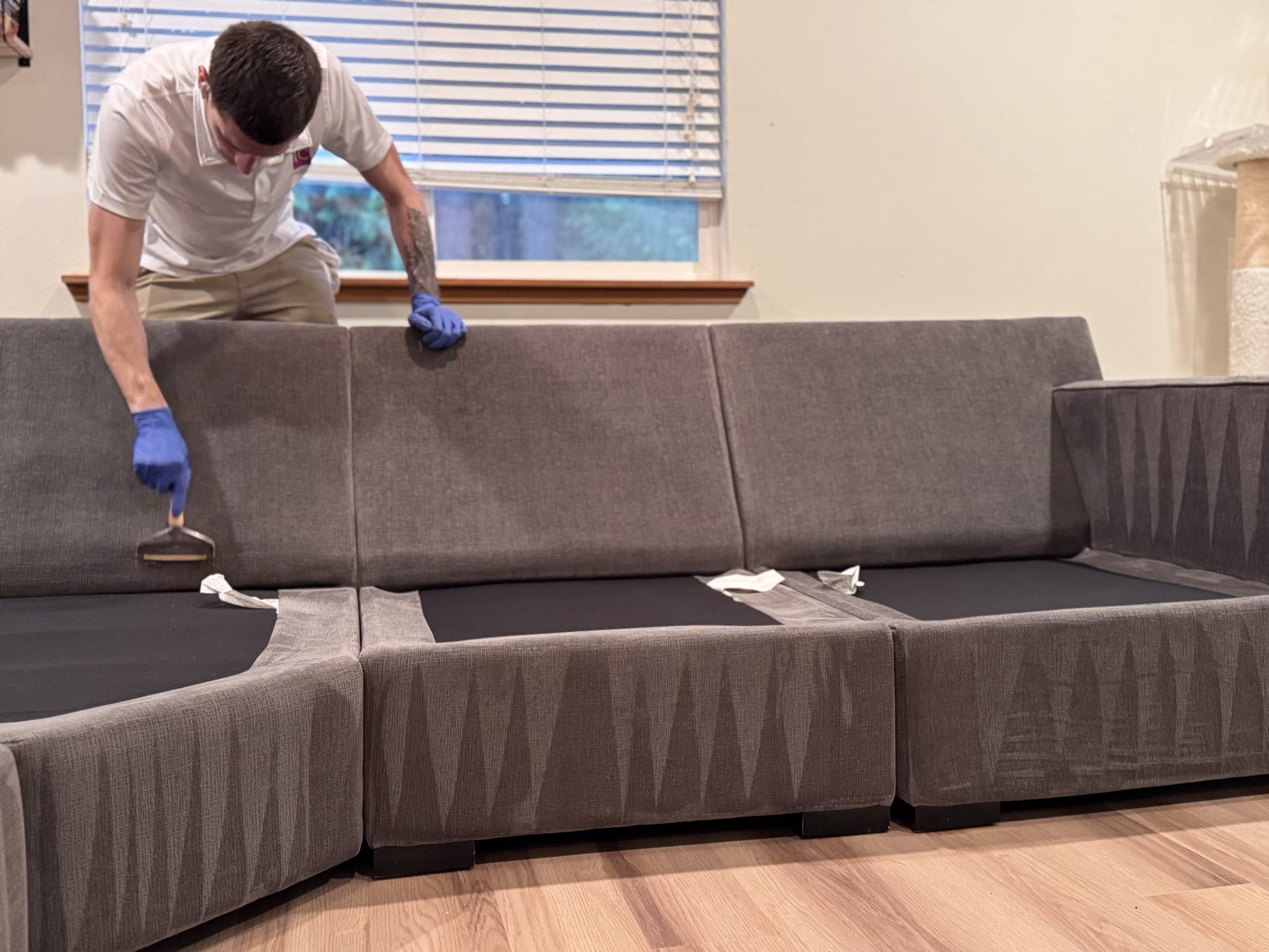 MagiClean technician cleaning the back cushions of a large L-shaped sectional in a Seattle home, seat cushions removed
